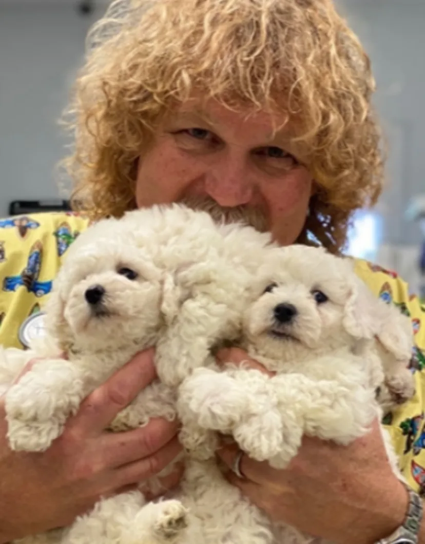 Dr. Mikel Athon holding white puppies